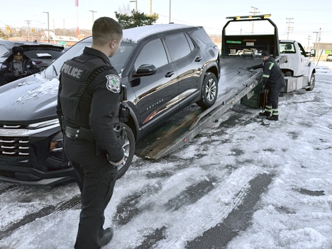 An Oak Park Michigan Department of Public Safety officer watches as a car is loaded onto a tow truck.