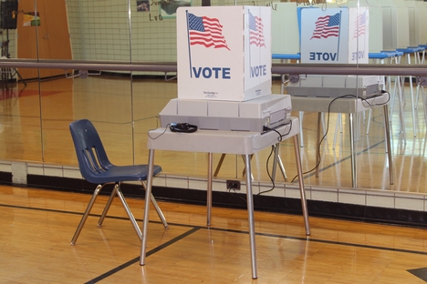 A voting machine stands in front of a mirrored wall.