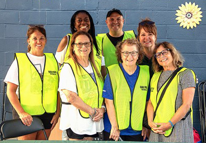 A group of seven wearing high visibility vests smiling at the camera.