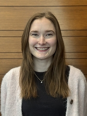 A head-and-shoulders photo of a woman with brown hair wearing a white sweater and black shirt.