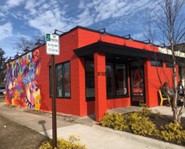 A red commercial building in Oak Park Michigan with a flat roof and colorful mural.