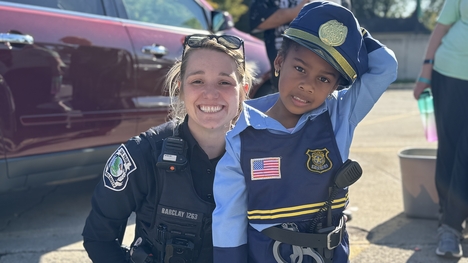 An Oak Park Department of Public Safety officer kneels next to a boy dressed as a policeman for Halloween.