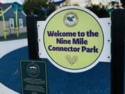 A round sign that says "Welcome to the Nine Mile Connector Park" in Oak Park Michigan.