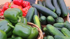 A close-up of cucumbers and peppers in baskets.