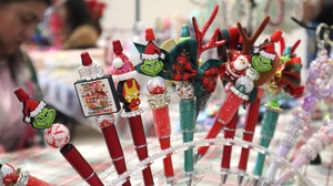 Ink pens, decorated with various Christmas designs are displayed in an acrylic stand.