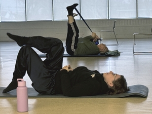 Two people lay on their back strecthing their legs in a stretching class in Oak Park Michigan. 