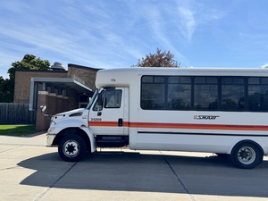 A white passenger bus is parked outside a recreation center building.