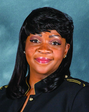 A headshot of a woman with black hair wearing a black blouse smiling at the camera.